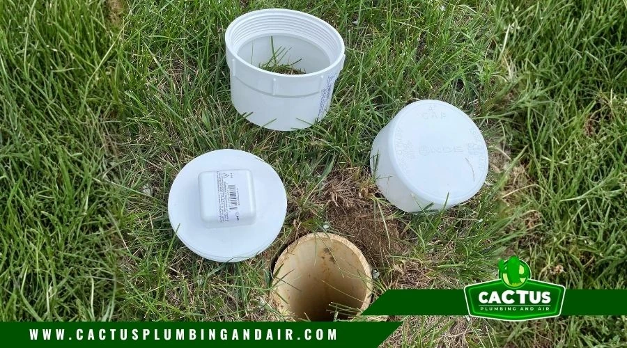outdoor sewer cleanout pipe with white PVC cap near a home foundation